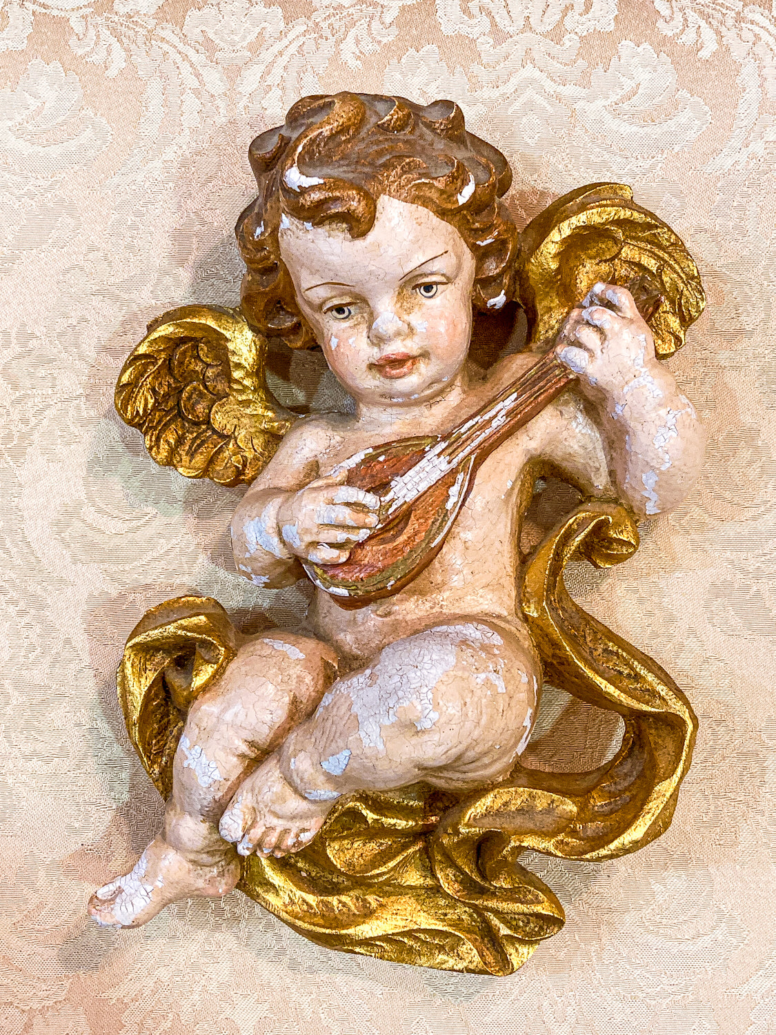 Decorative angel figure with gold accents on a textured beige background 20th Century Hand Painted Gessoed Gilded Cherub Wall Hanging Sculpture
