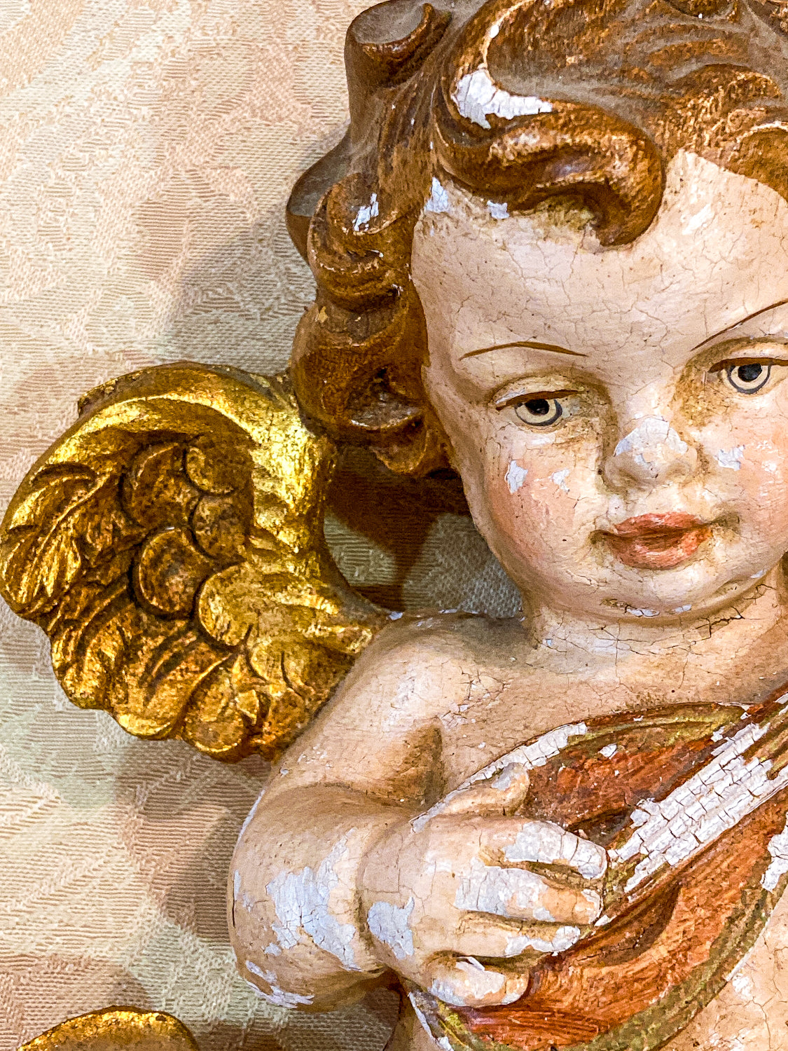 Close-up of a cherub with gold wings and a musical instrument on a textured beige background 20th Century Hand Painted Gessoed Gilded Cherub Wall Hanging Sculpture