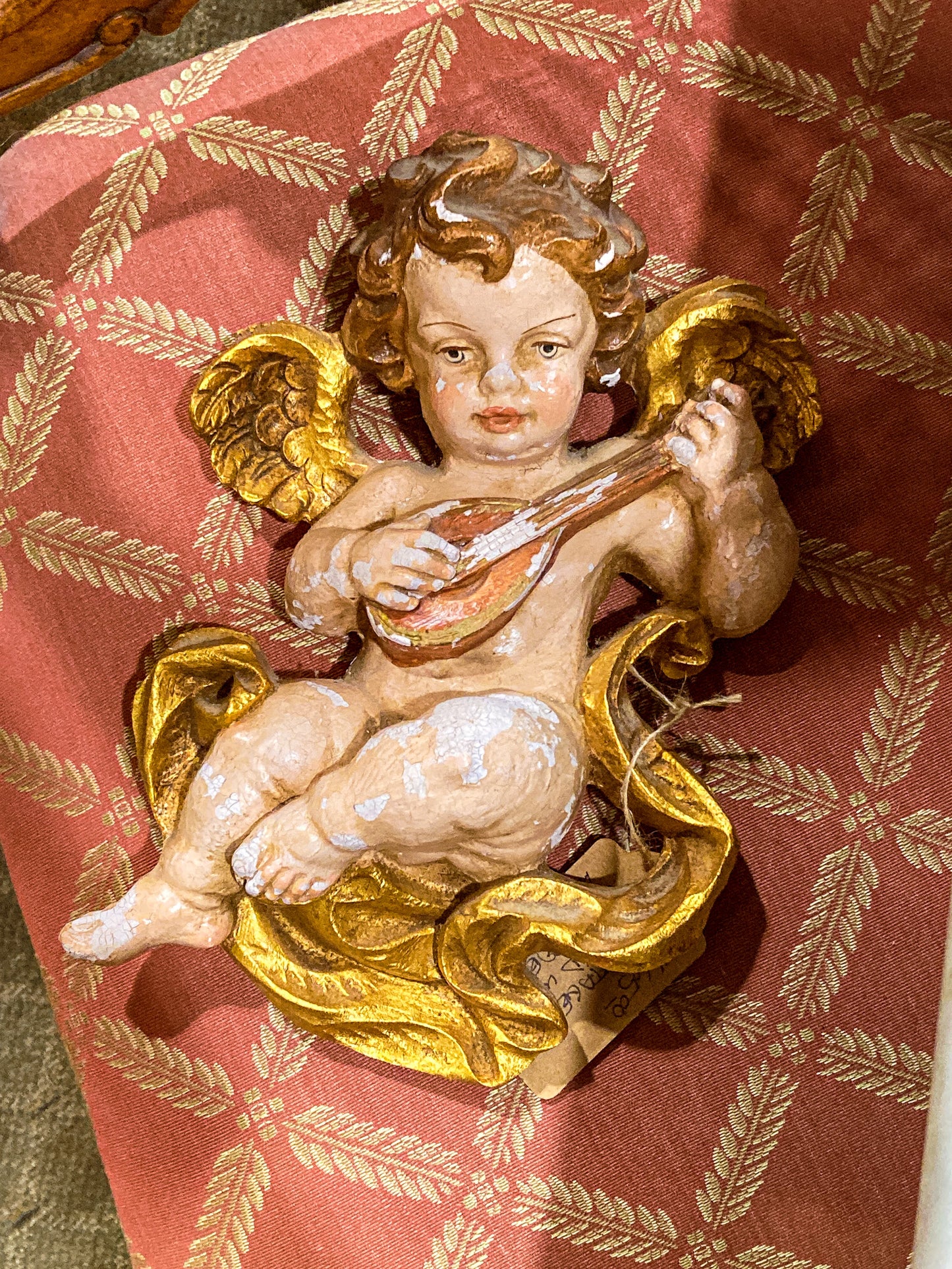 Decorative angel figurine with gold wings on a red fabric background 20th Century Hand Painted Gessoed Gilded Cherub Wall Hanging Sculpture