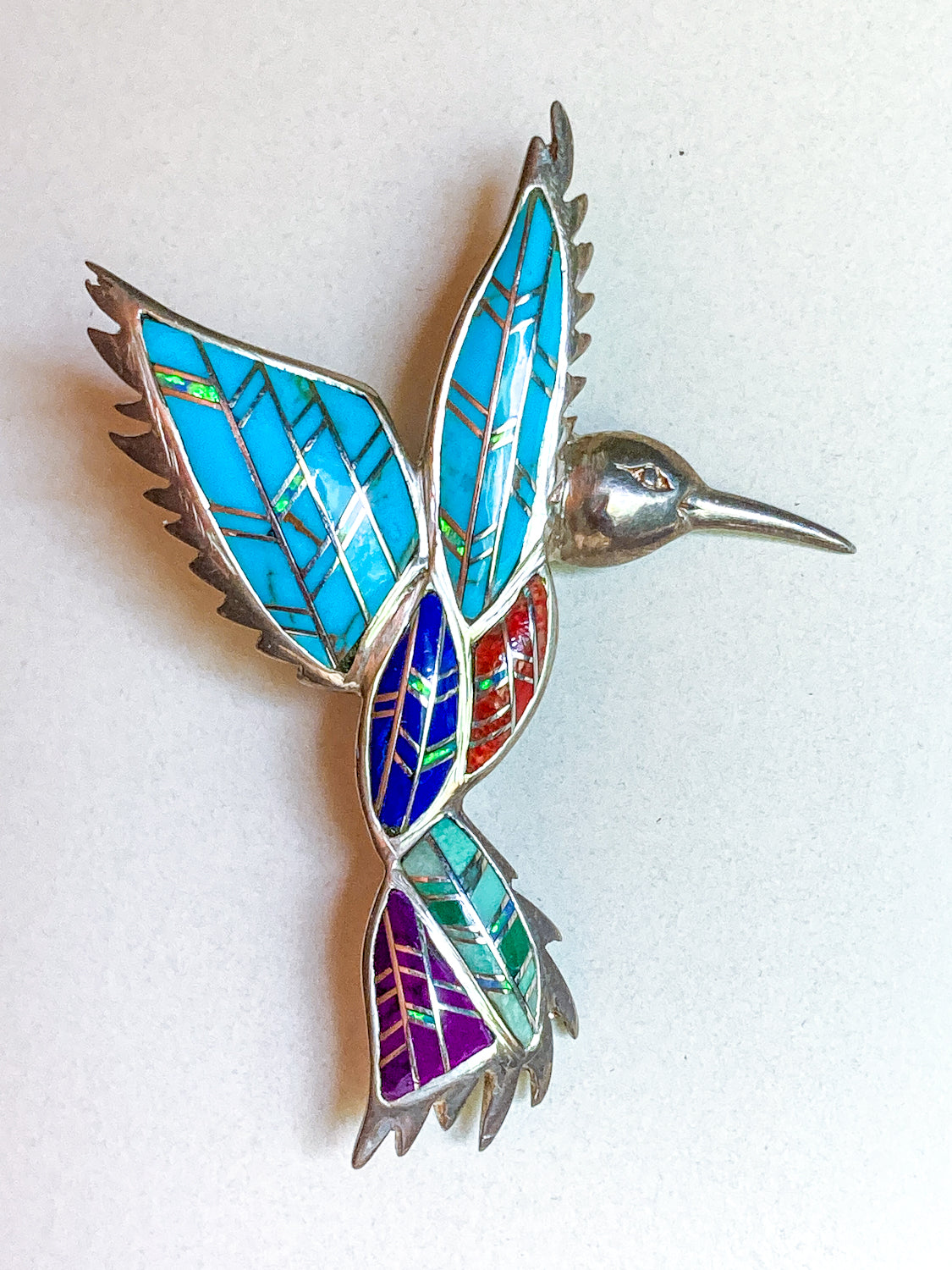 Colorful hummingbird-shaped brooch with mosaic pattern on a white Vintage Sterling Silver Turquoise Gemstone Mosaic Inlay Hummingbird Broochbackground